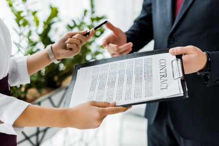 partial view of businesspeople signing contract in office