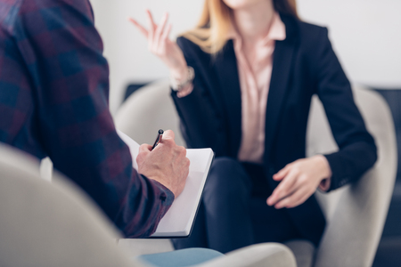cropped image of businesswoman in suit giving interview to journalist and he taking notes in officeの写真素材