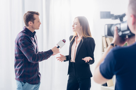 beautiful businesswoman in formal wear giving interview to journalist and gesturing in officeの写真素材