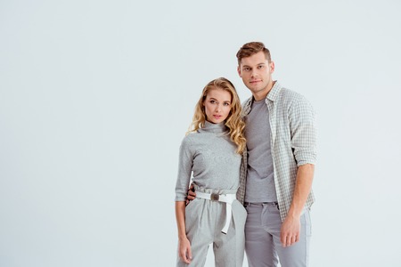 beautiful young couple looking at camera and posing isolated on grey