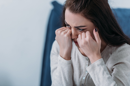 selective focus of depressed woman crying and wiping tears with copy spaceの写真素材