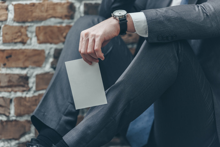 cropped view of man in grey suit sitting and holding photo on brown textured background in room, grieving disorder conceptの写真素材
