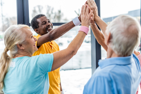 happy senior multicultural sportspeople putting hands together at gymの写真素材