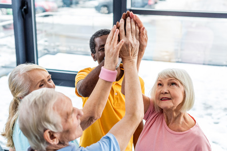 high angle view of senior multicultural sportspeople putting hands together at gym