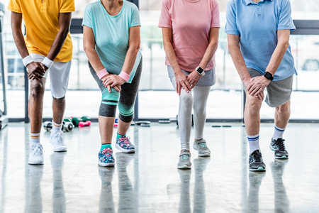cropped shot of senior sportspeople synchronous stretching at gymの写真素材