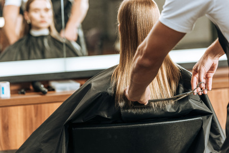 cropped shot of hairdresser cutting hair to beautiful young woman in beauty salonの写真素材