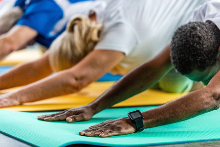 african american sportsman with smartwatch exercising near friends at gym