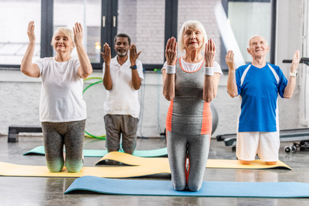 multiethnic senior athletes synchronous exercising on fitness mats at gymの写真素材