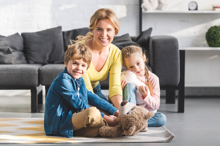 happy mother with cute little kids playing together and smiling at cameraの写真素材