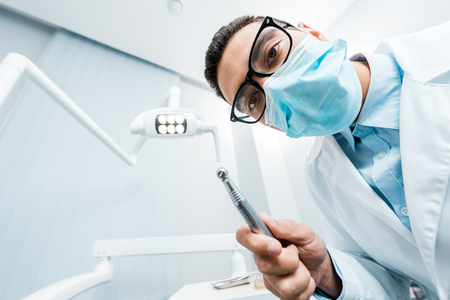 african american dentist in mask and glasses with drill in handの写真素材