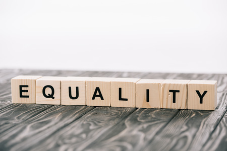 equality lettering made from alphabet cubes on wooden table on whiteの写真素材
