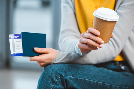 cropped  view of woman holding disposable cup in airportの写真素材