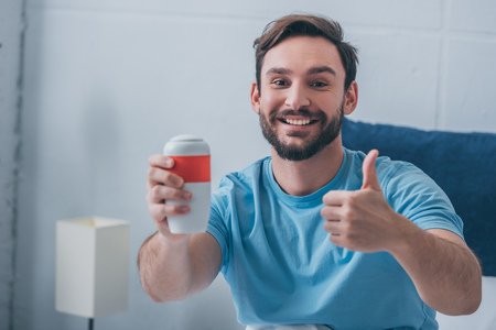 smiling man holding funeral urn, looking at camera and showing thumbs up signの写真素材