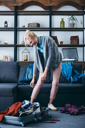 irritated woman packing clothes after breaking up with boyfriend in living roomの写真素材