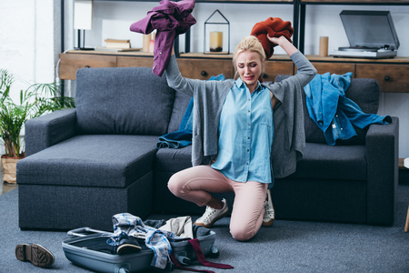 frustrated woman throwing clothes in living room after breaking up with boyfriendの写真素材