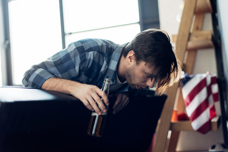 drunk man holding bottle and feeling nauseated after partyの写真素材