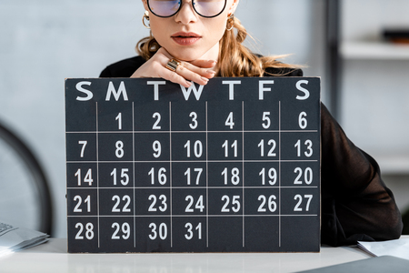 businesswoman in black clothes and glasses holding calendarの写真素材