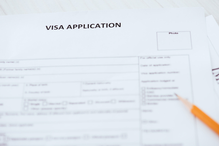 selective focus of visa application lettering on document near wooden pencilの写真素材