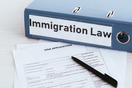 selective focus of folder with immigration law lettering near documentsの写真素材