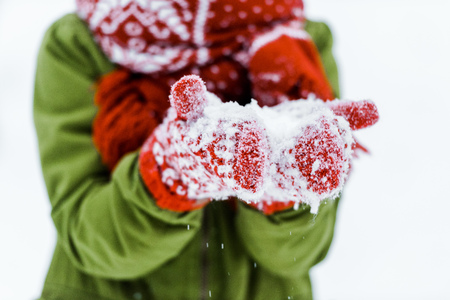 child with red gloves blowing white snowの写真素材