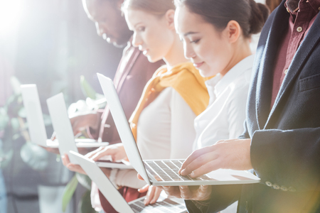 selective focus of businesspeople using laptops with backlit on backgroundの写真素材