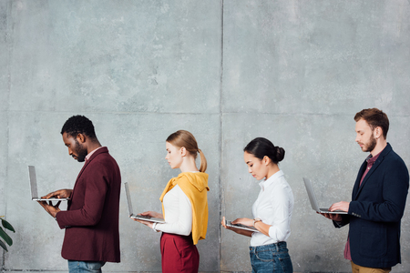 multiethnic casual businesspeople using laptops in waiting hall