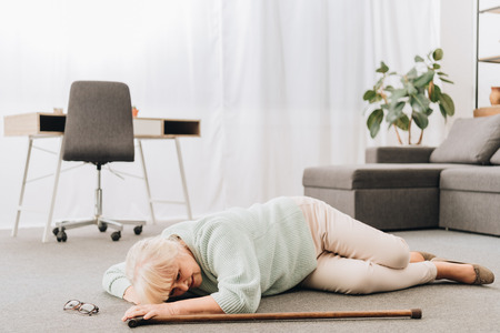 helpless retired woman lying on floor in living roomの写真素材