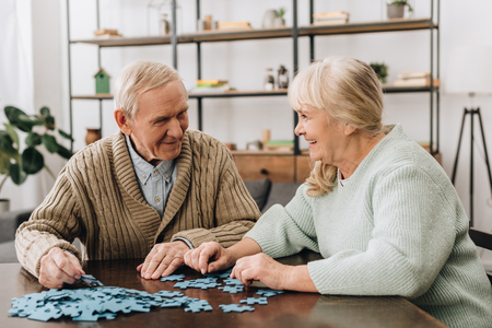 happy senior couple playing with puzzles at homeの写真素材
