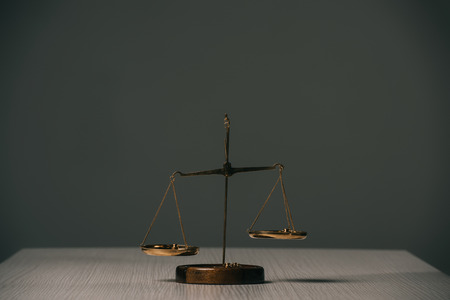 empty scales of justice on wooden table on grey