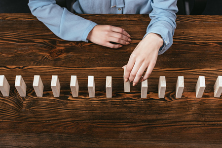 cropped view of woman picking wooden brick from row of blocks on deskの写真素材