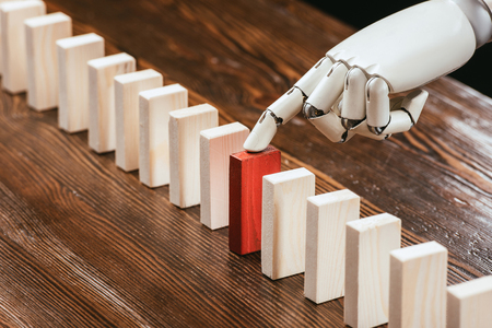 selective focus of robotic hand picking red wooden brick from row of blocks on deskの写真素材