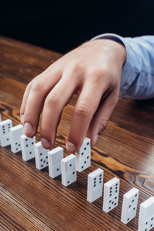 close up view of man picking domino from row on wooden deskの写真素材