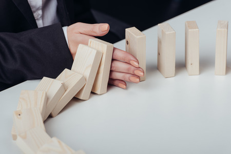 partial view of woman preventing wooden blocks from falling