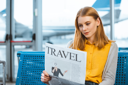 beautiful woman reading travel newspaper in departure loungeの写真素材