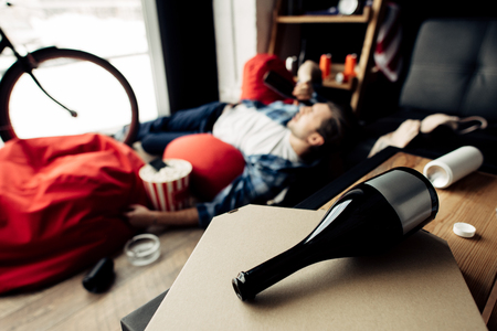 selective focus of bottle lying on pizza box with drunk man on backgroundの写真素材