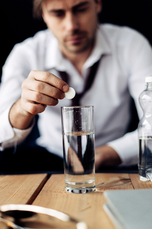 selective focus of man putting aspirin in glass of waterの写真素材