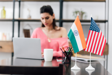 selective focus of american and indian flags on table and girl studying with laptop