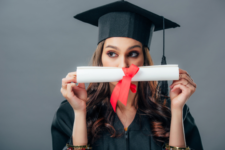 female indian student in graduation hat holding diploma, isolated on greyの写真素材