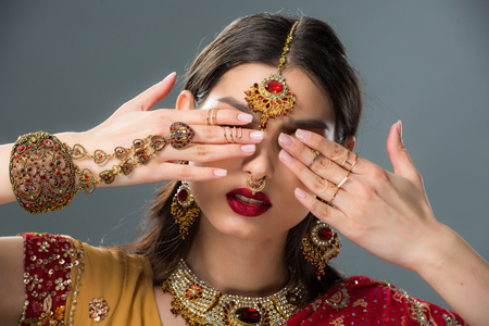 attractive indian woman with bindi closing eyes, isolated on grey