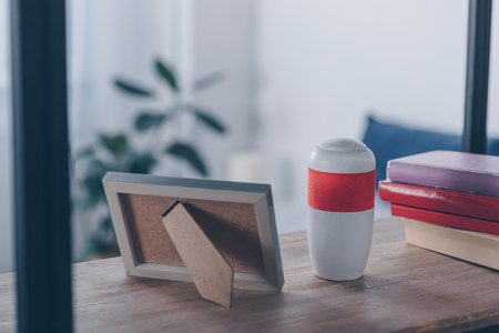 photo frame, books and funeral urn on wooden shelveの写真素材