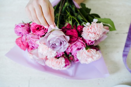 cropped view of female florist arranging bouquet with pink roses and carnationsの写真素材