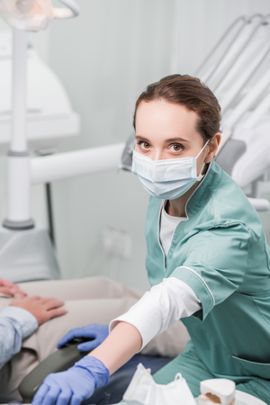 female dentist in mask and latex gloves near patientの写真素材