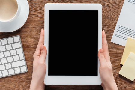 Cropped view of girl using digital tablet with blank screen at workplaceの写真素材