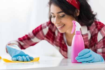 selective focus of smiling african american woman cleaning tableの写真素材