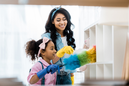 pretty african american woman with daughter cleaning houseの写真素材