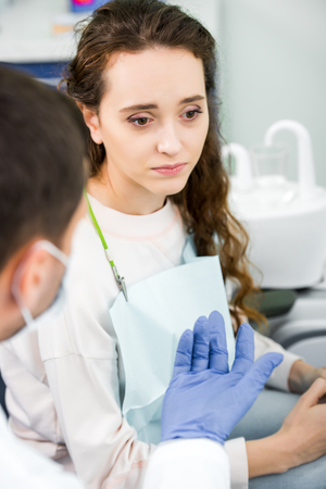 selective focus of pensive woman near dentist wearing latex glovesの写真素材
