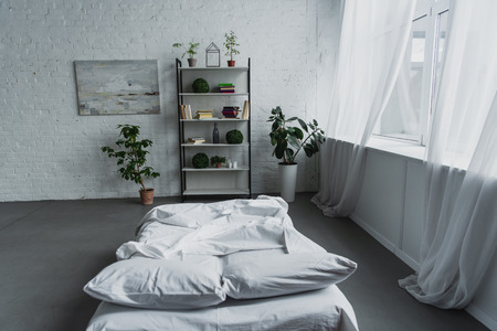 modern interior design of bedroom with rack, plants, bed, brick wall and copy spaceの写真素材