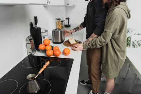 partial view of young couple preparing toasts together during breakfast in kitchenの写真素材