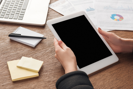 Partial view of woman posing with digital tablet with blank screen at workplaceの写真素材