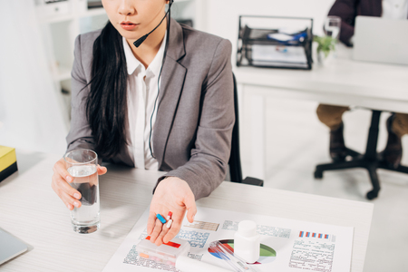 Cropped view of female operator holding pills and glass of waterの写真素材